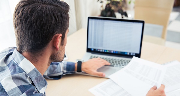 Man sitting at the table with bills and laptop